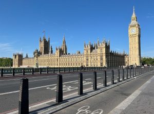 The Houses of Parliament and Big Ben viewed from Westminster Bridge under a clear blue sky.