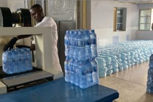Factory worker packaging bottled water at a Nigerian water production plant
